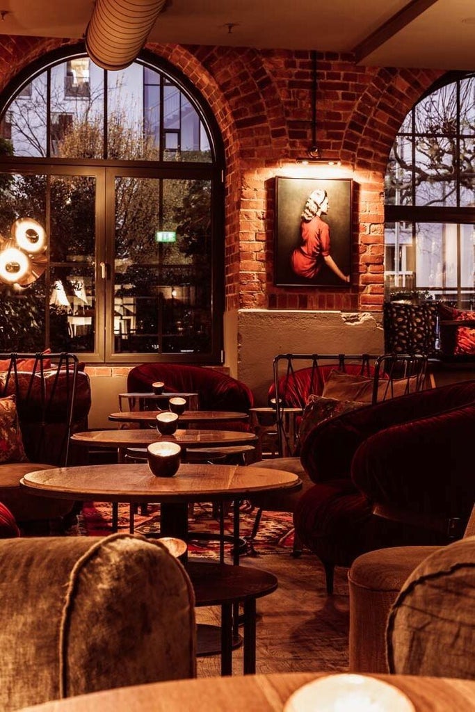 Boutique hotel lobby with exposed brick walls, modern wood accents, industrial architecture and vintage machinery on display