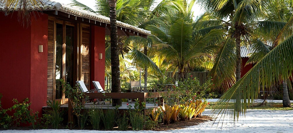 Luxurious wooden bungalow with rustic charm, nestled in Brazilian landscape, featuring elegant furnishings and panoramic tropical forest views through large windows