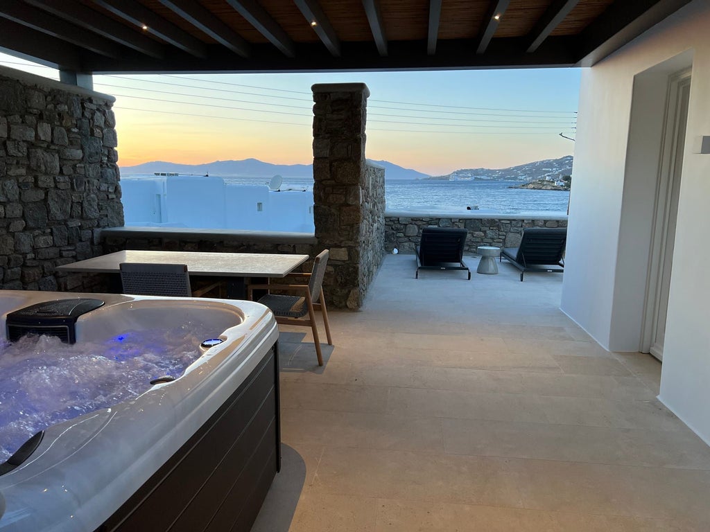 Luxurious one-bedroom suite with stunning sea view, private hot tub, and elegant white Cycladic design in Mykonos, Greece.