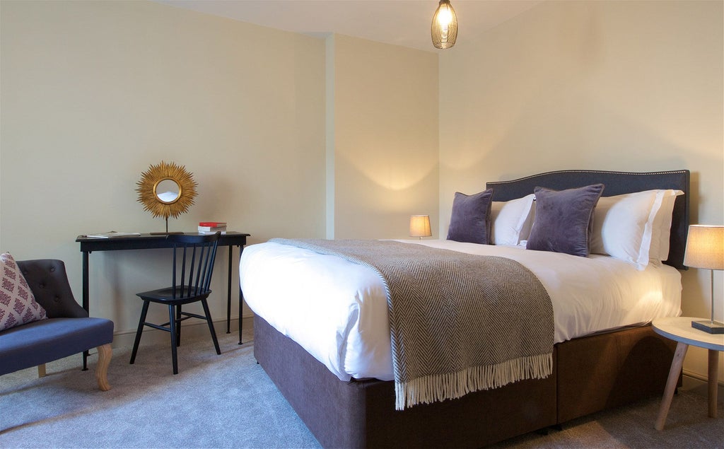 Elegant modern hotel room with plush king-sized bed, contemporary furnishings, warm lighting, and stylish decor in a boutique United Kingdom apartment-style setting