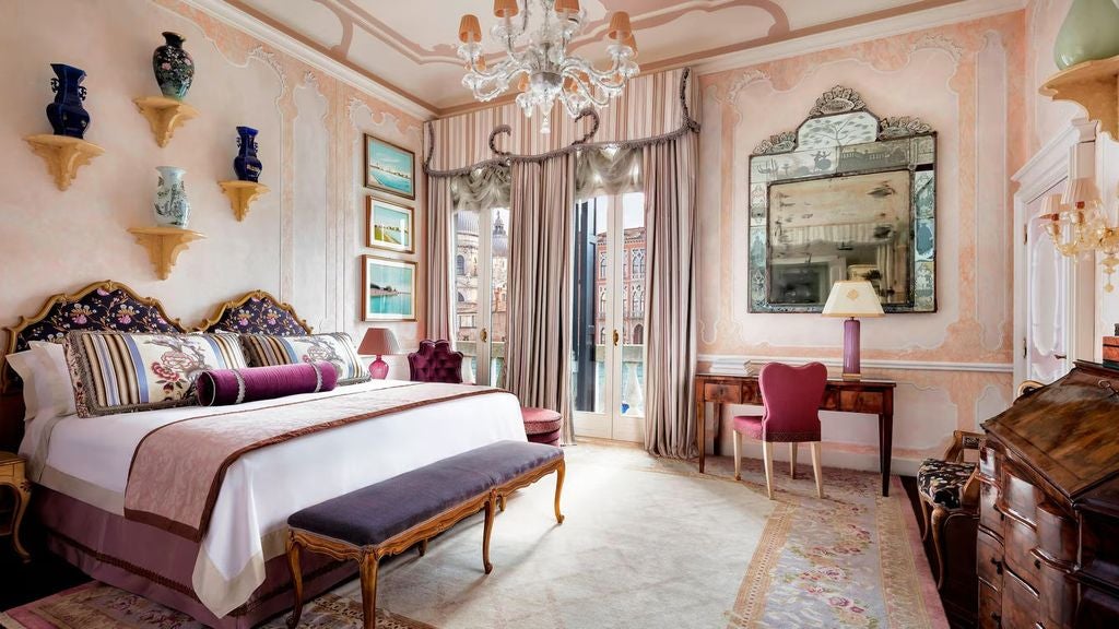 Opulent Venetian suite with gilded mirrors, crystal chandeliers, striped silk wallpaper, antique furniture, and Grand Canal views