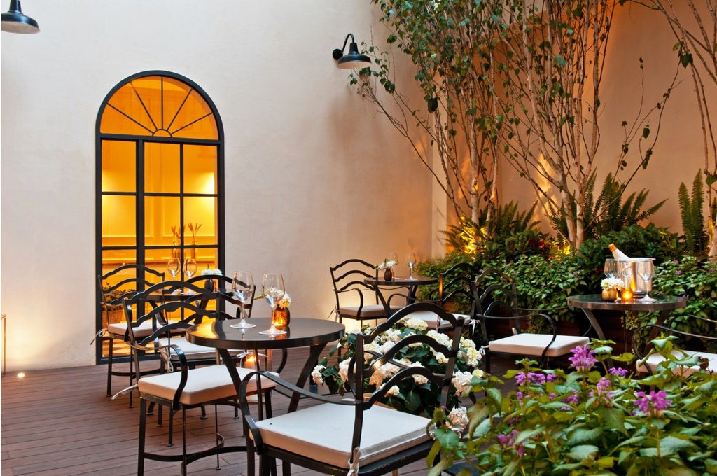 Elegant boutique hotel facade with charming wrought iron balconies, warm lighting, and lush potted plants in Rome's historic district