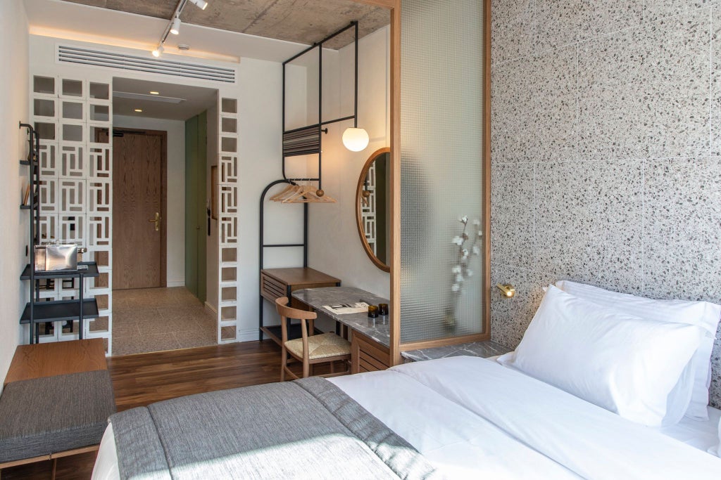 Minimalist medium hotel room with warm wood accents, crisp white linens, and city view, showcasing contemporary Greek design in Athens' boutique Ergon House.