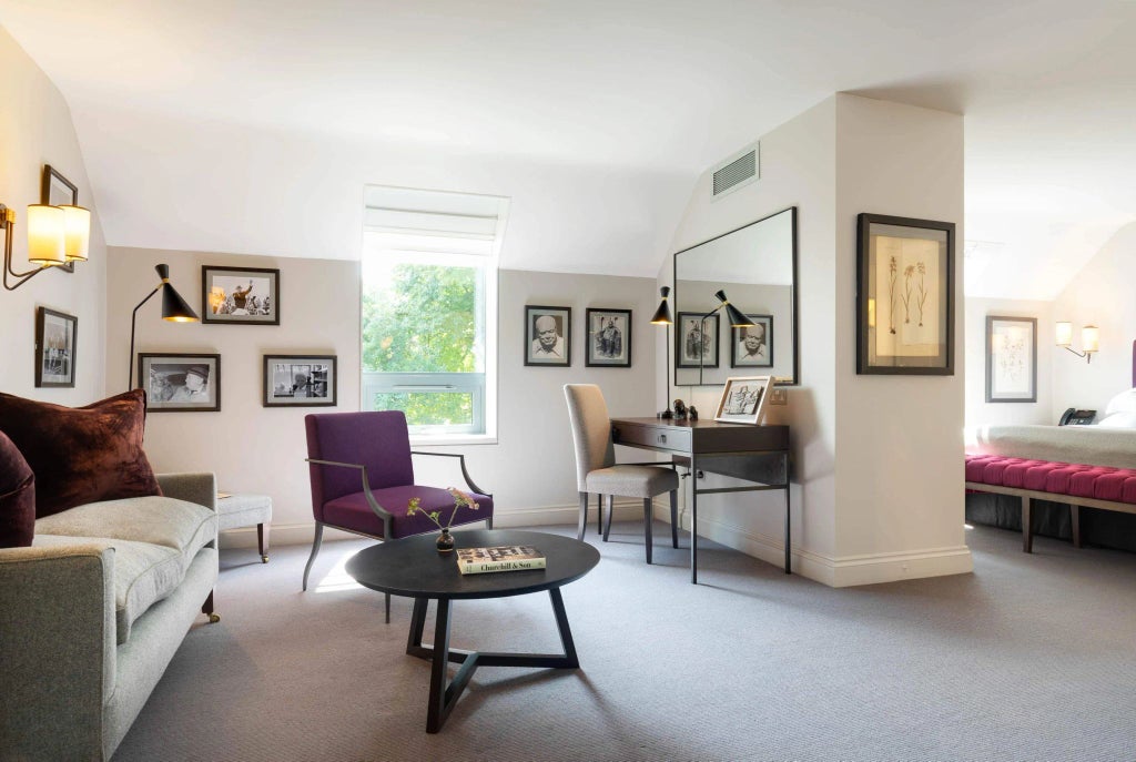 Elegant Churchill Suite at historic Old Parsonage Hotel, featuring plush bedding, rich wooden furnishings, and refined British architectural details in soft neutral tones