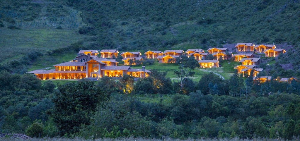 Luxurious mountain lodge nestled in Sacred Valley, featuring stone walls, terrace views, and Andean peaks in misty background