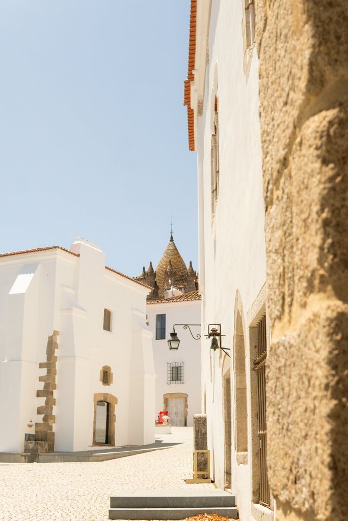 Tour guide and travelers exploring historic Évora's charming cobblestone streets lined with whitewashed buildings and Roman architecture