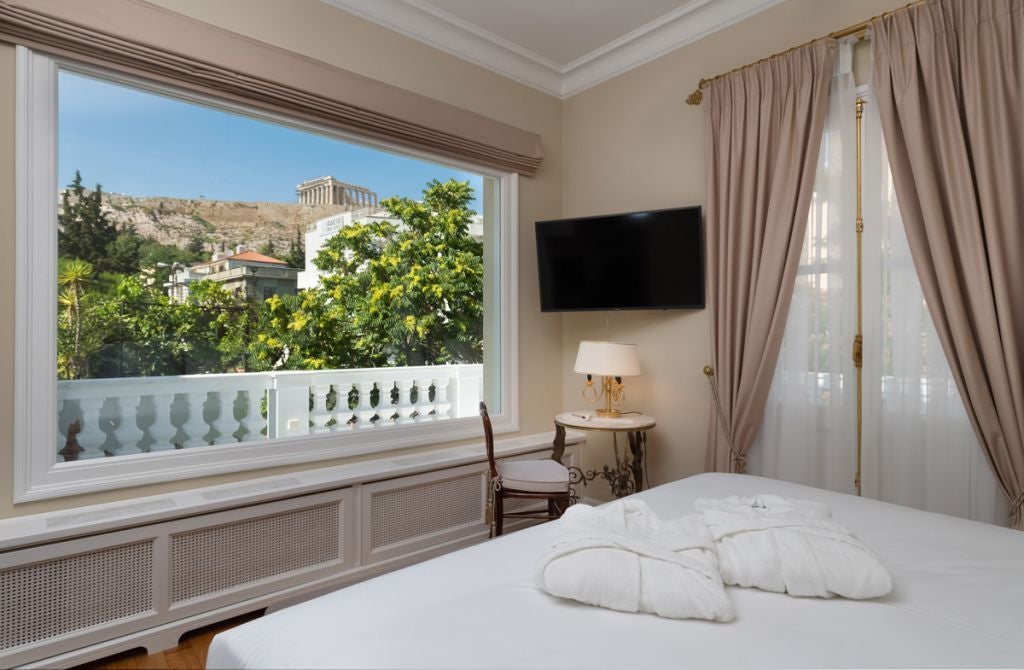 Elegant boutique hotel exterior with neoclassical architecture, featuring marble columns, ornate balconies and warm evening lighting in Athens