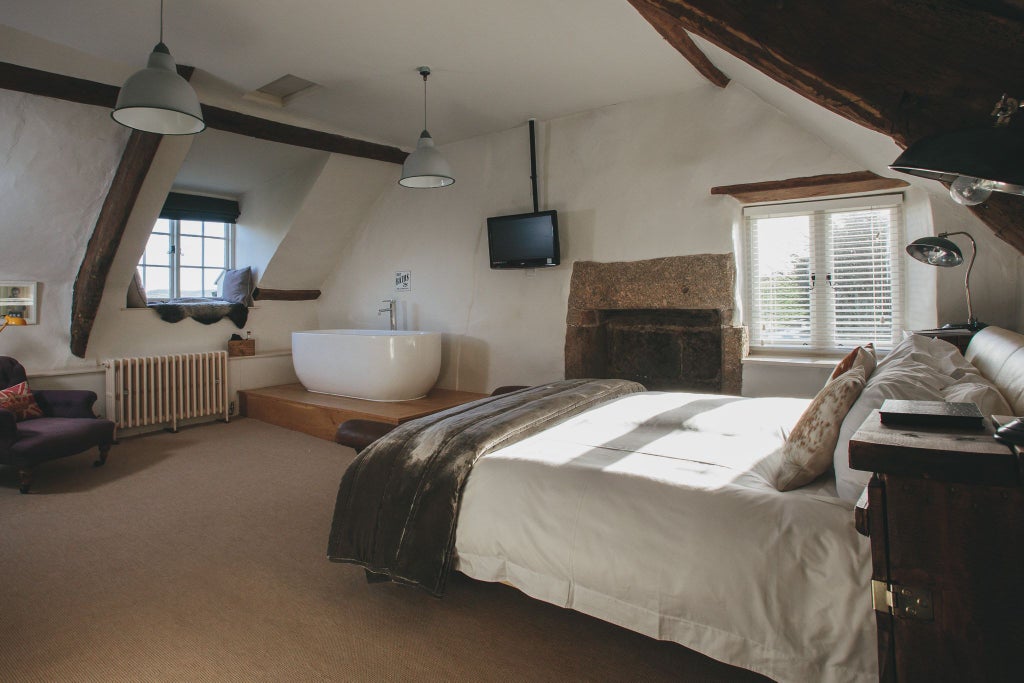 Historic stone farmhouse hotel nestled in lush Devon countryside, featuring traditional architectural details and serene green landscape with rolling hills in background