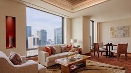 Elegant deluxe hotel room with panoramic city views, minimalist Japanese design, plush king bed, and sophisticated neutral color palette in Peninsula Tokyo.