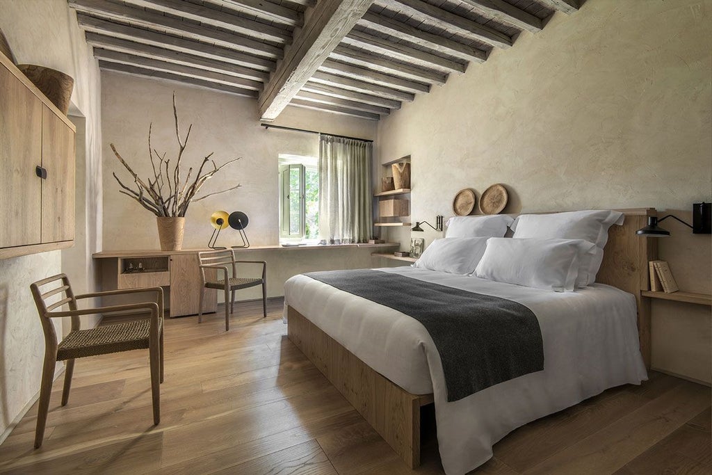 Elegant Italian junior suite with rustic wooden beams, plush king bed, and panoramic countryside views at Badia di Pomaio in Tuscany