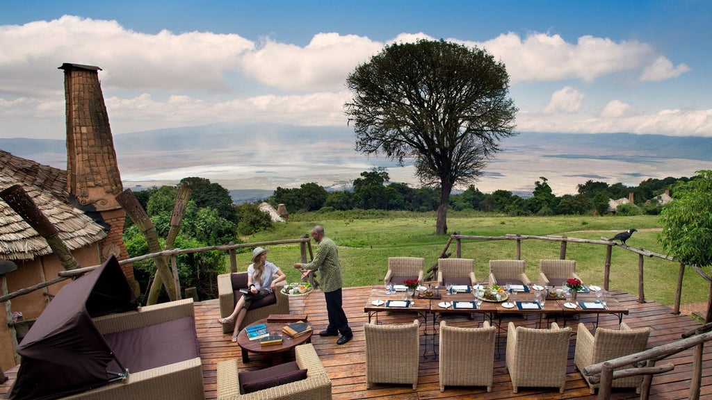 Colonial-style luxury lodge perched on Ngorongoro Crater rim with thatched roofs, panoramic safari views, and elegant terraces at sunset