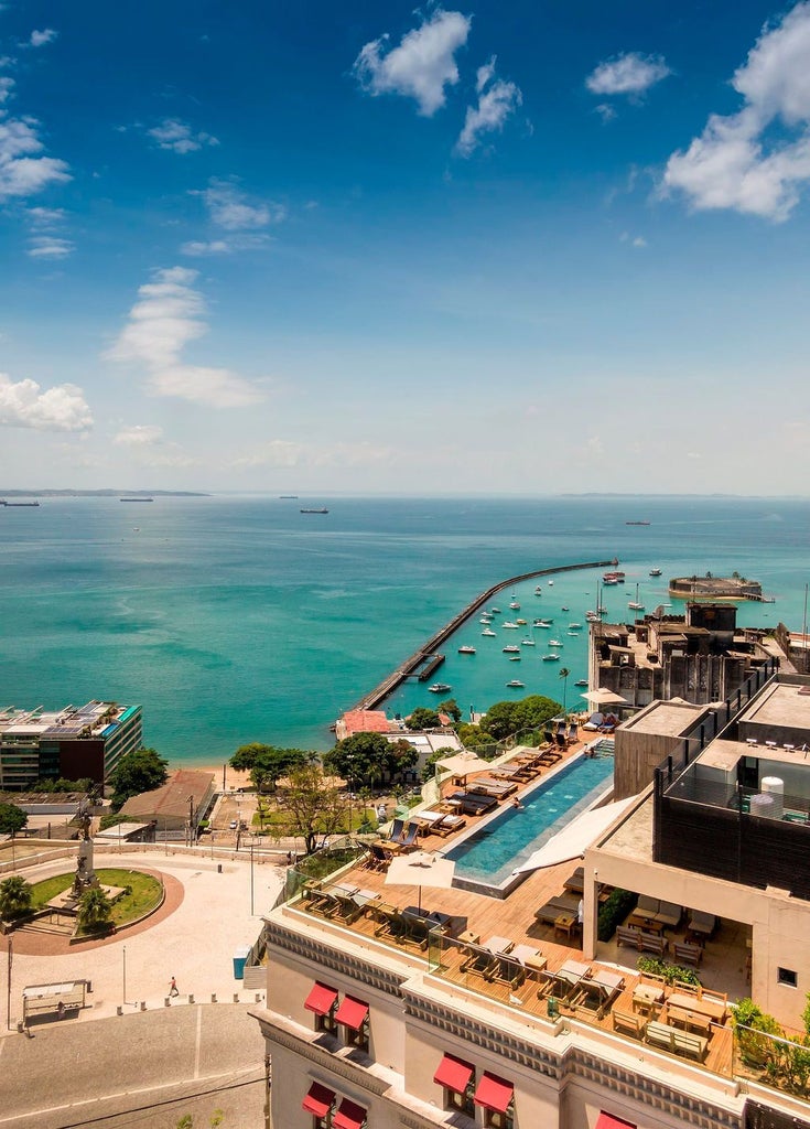 Luxurious Fasano hotel exterior in Salvador, Brazil, featuring modern architecture with sleek lines, warm-toned facade, and elegant tropical landscaping at sunset