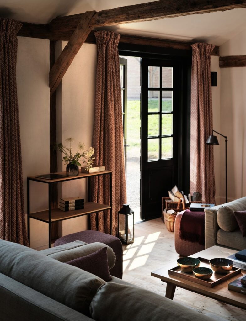 Elegant rustic bedroom in Transylvanian stone house, featuring wooden floors, antique furniture, and warm ambient lighting with mountain view