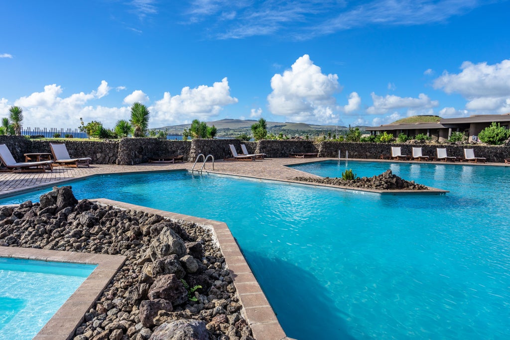 Modern luxury resort with curved stone walls and floor-to-ceiling windows overlooking the Pacific Ocean on Easter Island's coast