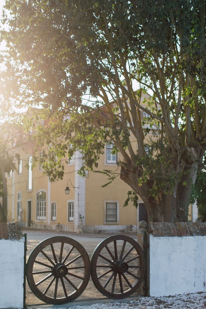 Luxurious stone country house with traditional Portuguese architecture, surrounded by lush green landscape and elegant spa terrace at sunset