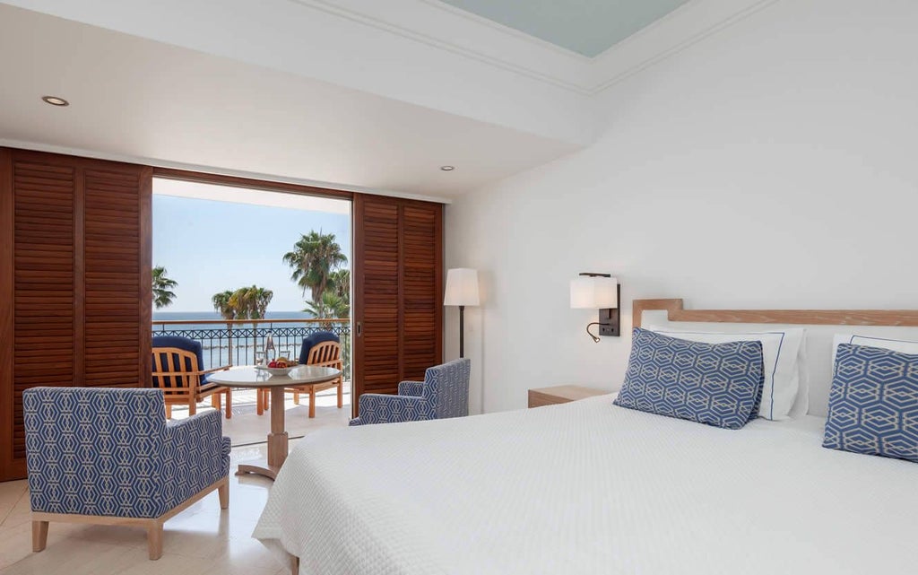 Luxurious deluxe sea view room at coastal Cyprus hotel with modern decor, plush king bed, and panoramic azure Mediterranean waters through large windows