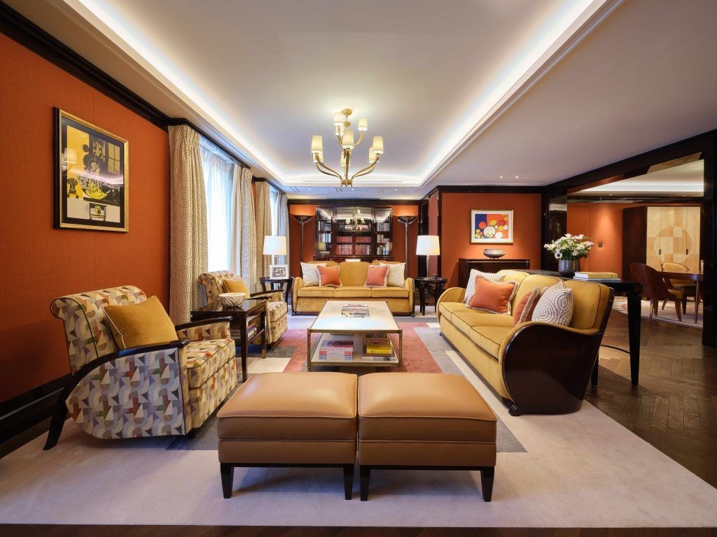 Elegant classic suite interior in Mayfair, London, featuring luxurious cream-colored furnishings, plush king bed, and sophisticated Art Deco-inspired decor