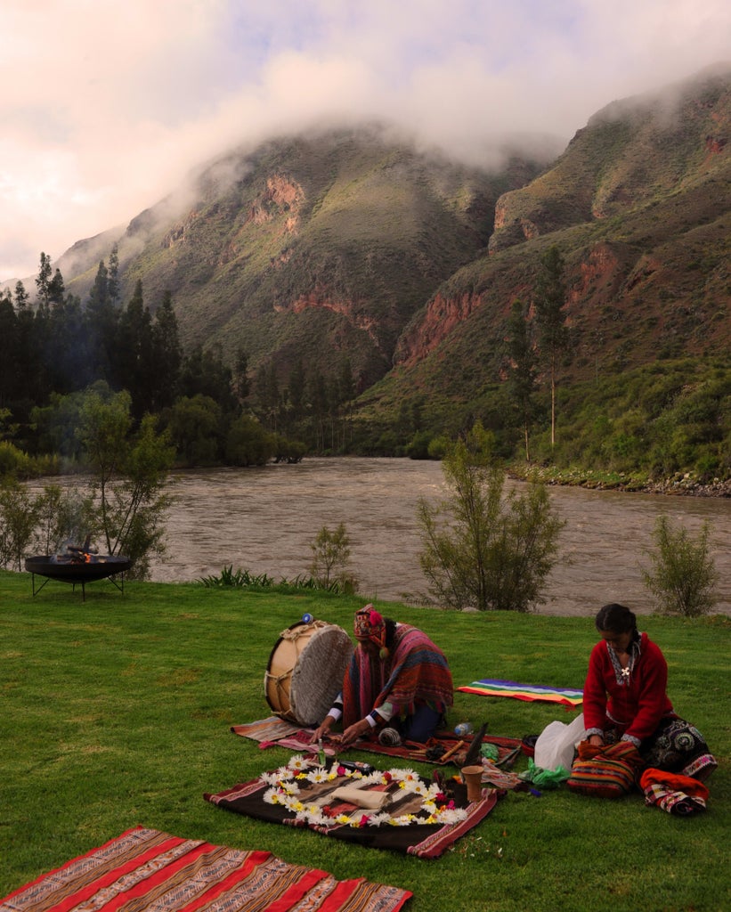 Terraced luxury hotel nestled in Sacred Valley, Peru, with stone buildings, green gardens and Andes mountains towering in background