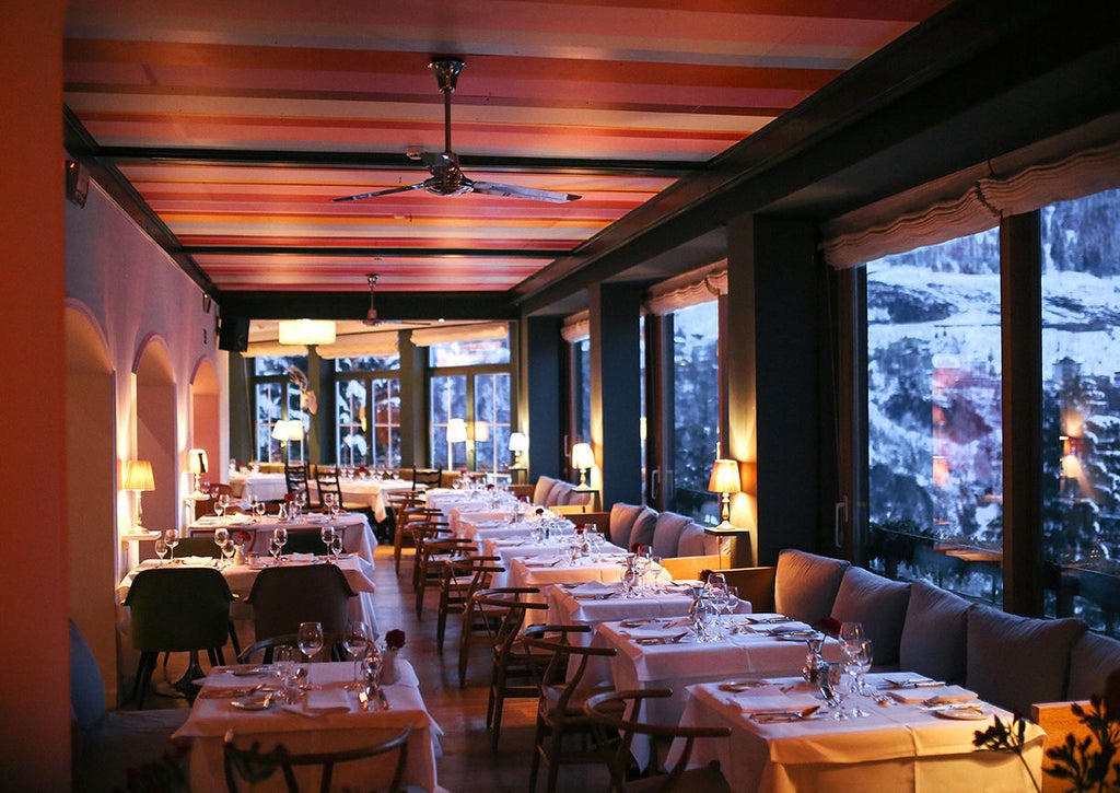 Historic alpine spa hotel with sleek modern glass balconies nestled in snowy Austrian mountains, white facade glowing in winter light