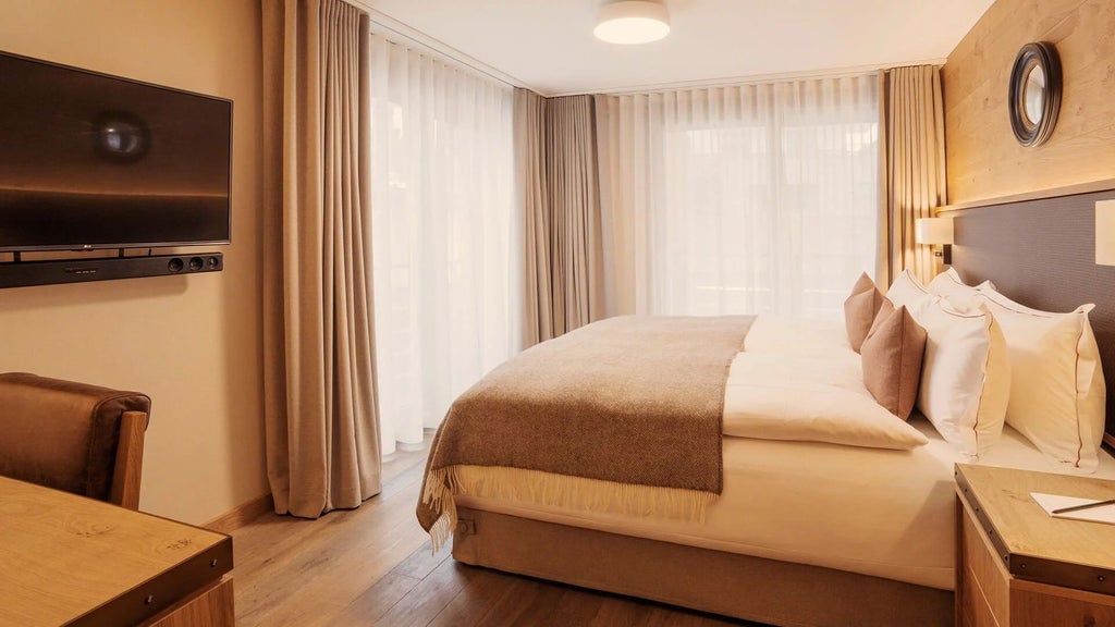 Luxurious alpine-style double room with wooden accents, plush white bedding, large windows overlooking Swiss mountain landscape at scenset hotel