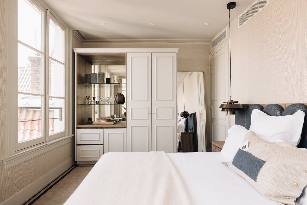 Elegant merchant-style hotel room in Netherlands with rich mahogany furniture, soft neutral linens, and refined contemporary design highlighting sophisticated urban comfort