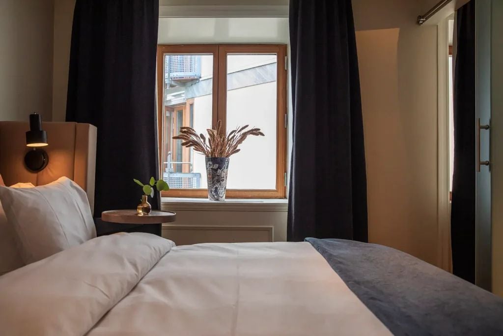 Elegant junior suite at Scenset Hotel, Sweden, featuring plush king bed, sophisticated neutral decor, large windows with soft natural light, and refined modern furnishings