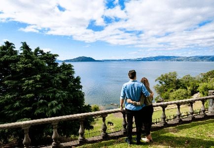 Spacious Garden View Lodge Suite with plush king bed, elegant wooden furnishings, and panoramic views of lush New Zealand landscape and verdant gardens