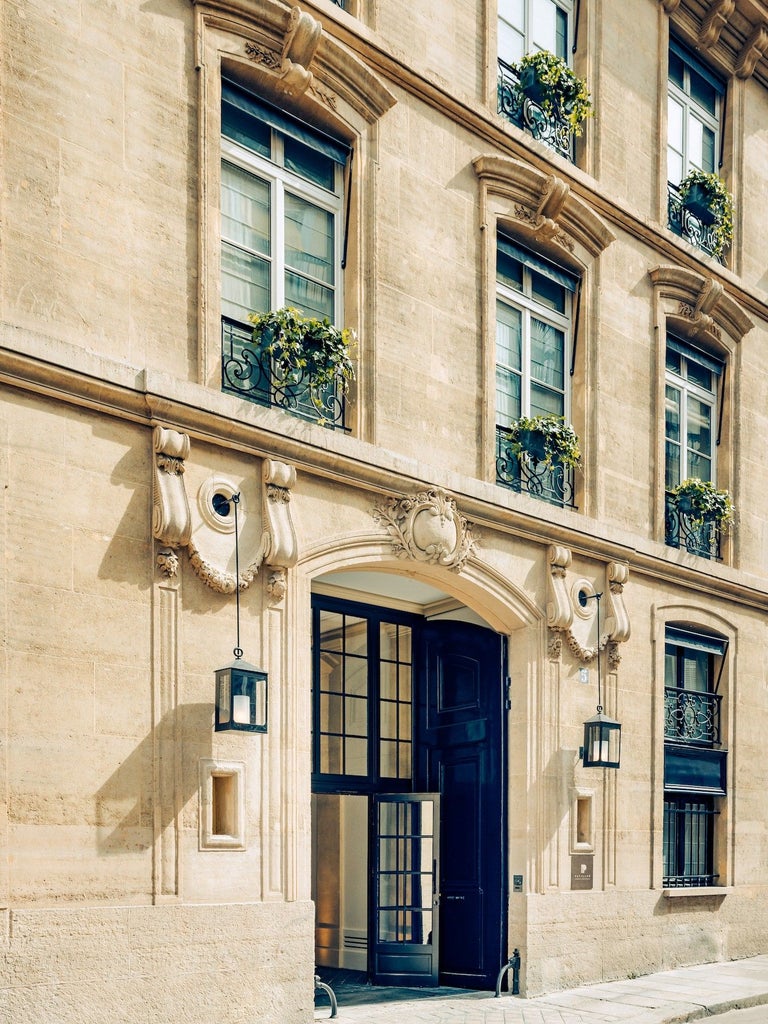 Elegant Art Deco hotel facade with brass fixtures, ornate sconces, and emerald green awnings in Paris's Saint-Germain district