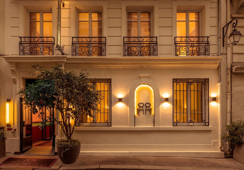 Elegant boutique hotel facade in French countryside, with soft pastel-colored exterior, ornate balconies, and lush garden framing historic architectural charm