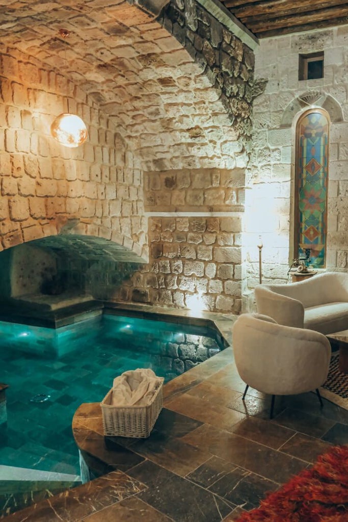 Luxurious stone-walled boutique hotel with vintage decor, nestled in a historic Cappadocian landscape with cave-like rooms and panoramic mountain views