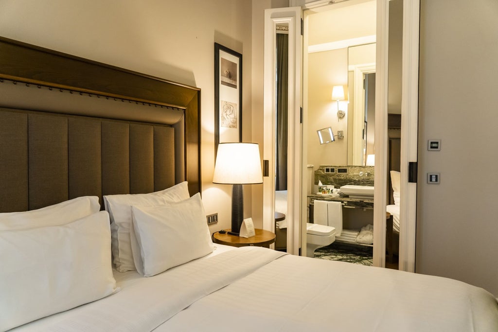 Elegant deluxe king room with plush white bedding, dark hardwood floors, large windows, and contemporary Turkish-inspired luxury hotel decor in Istanbul.