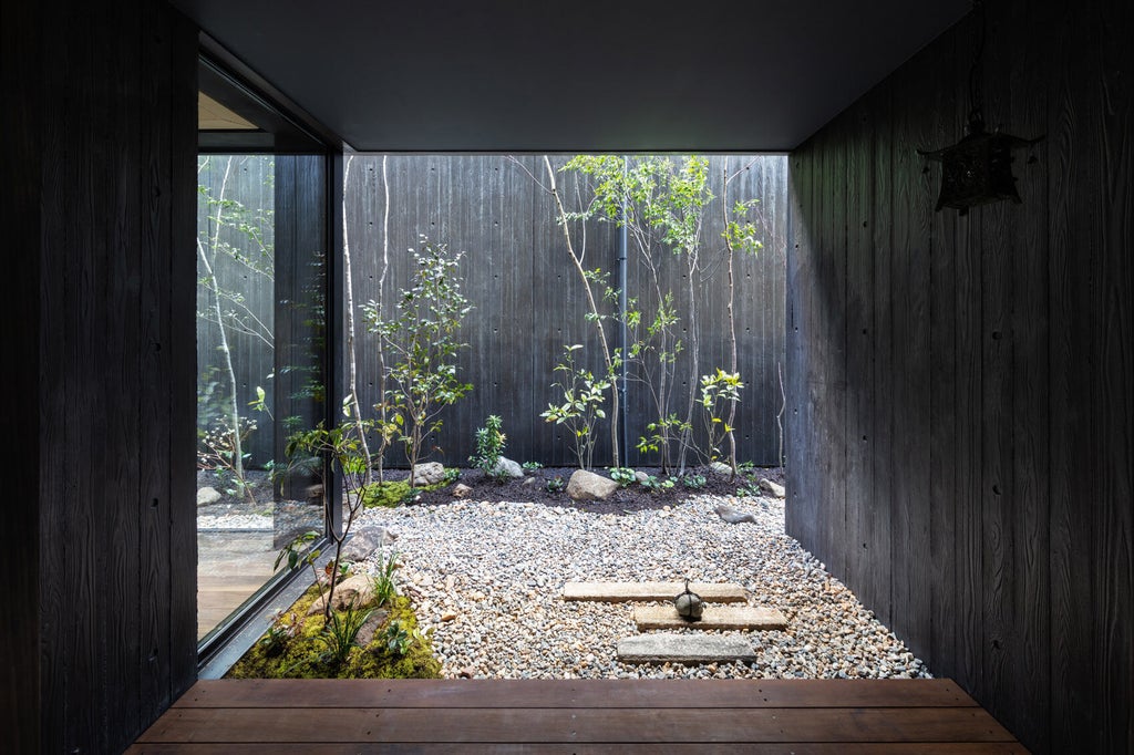 Modern Japanese hotel entrance featuring a minimalist stone path, traditional wooden gates, and serene lantern lighting at dusk