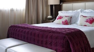 Elegant twin-bedded hotel room with sophisticated white and grey decor, modern furnishings, and luxurious textiles at a premier United Kingdom accommodation