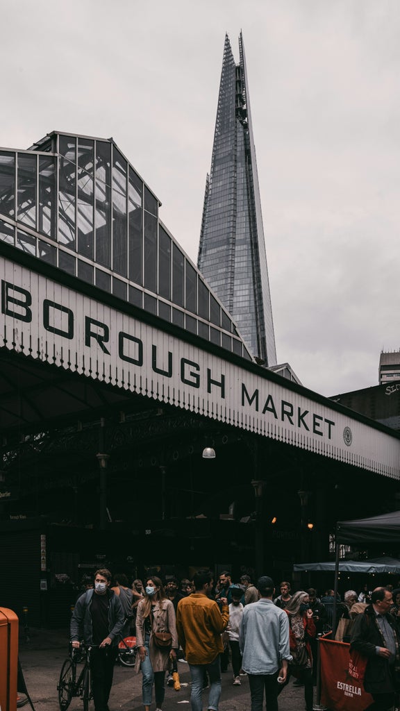 Sunlit Borough Market stalls with artisan vendors, vibrant produce displays, and culinary enthusiasts exploring gourmet food selections during afternoon peak hours