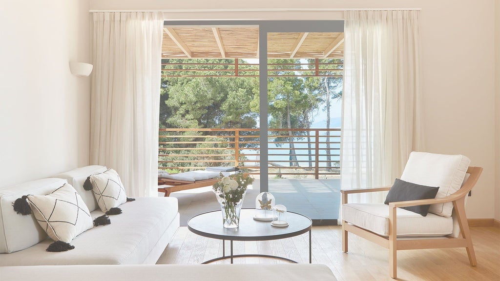 Luxurious sunset-view suite at ELIVI Skiathos hotel, featuring minimalist design, white decor, private balcony overlooking Aegean Sea's golden horizon