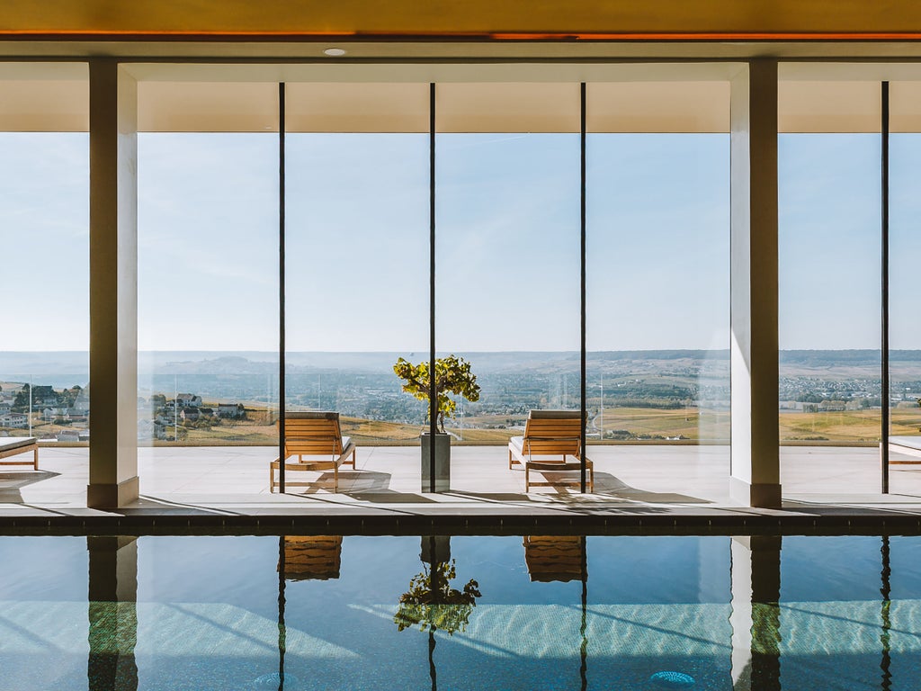 Elegant infinity pool overlooking French vineyards at sunset, with luxurious lounge chairs and panoramic Champagne valley views