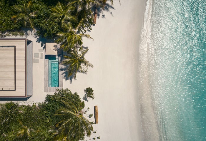 Luxurious overwater villa in Maldives with private infinity pool, wooden sundeck and glass panels overlooking turquoise lagoon waters