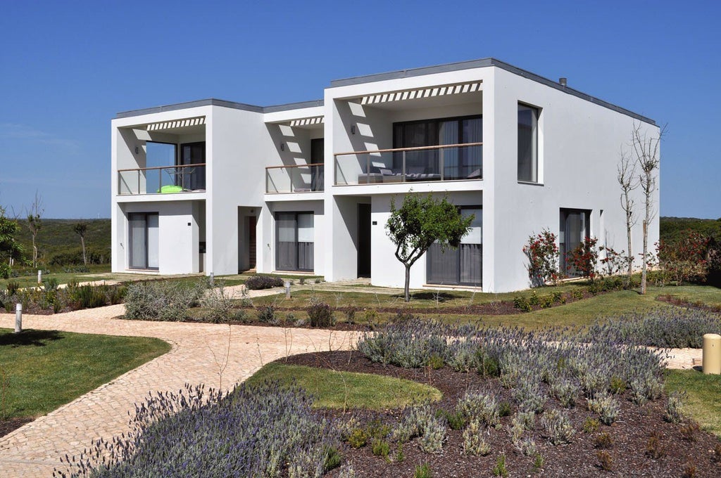 Spacious modern Bay House suite at Martinhal Sagres Beach Resort, featuring elegant white decor, large windows overlooking coastal landscape, and minimalist design