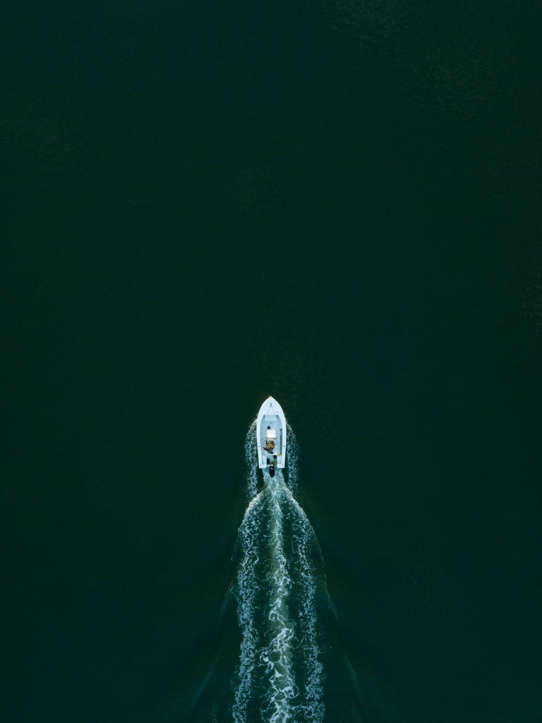 Luxurious yacht sailing past stone cliffs along Croatia's rugged coastline, with turquoise waters and small islands in distance