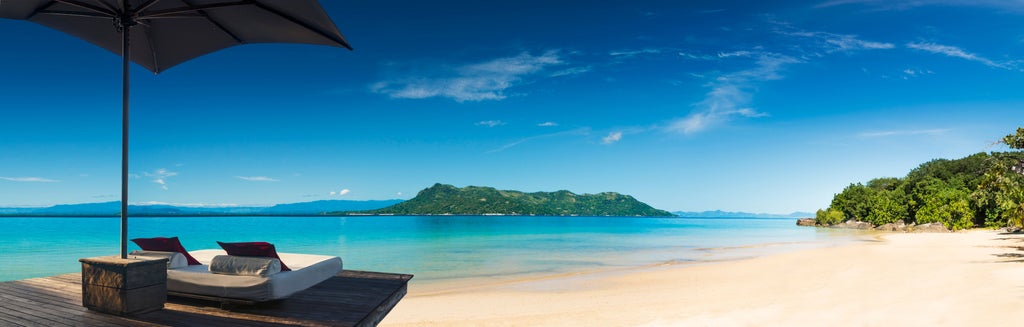 Luxury treehouse-style bungalow with thatched roof overlooking pristine beach and turquoise waters of Madagascar's northern coast