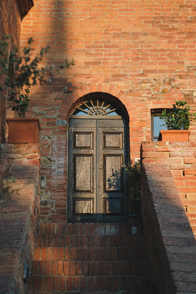 Elegant Tuscan boutique hotel nestled in countryside, featuring stone facade, terracotta roof tiles and manicured Mediterranean garden