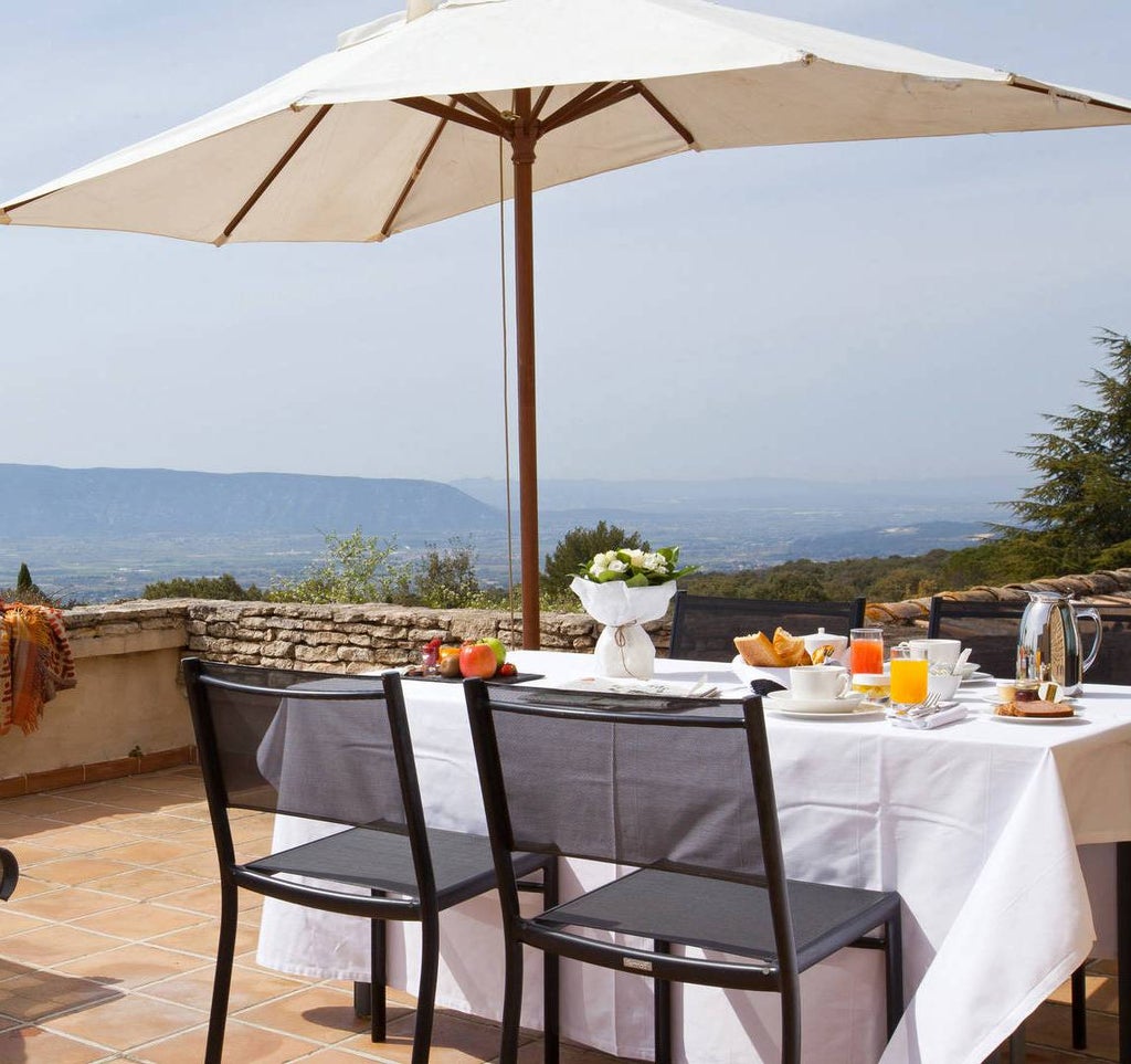 Elegant stone-built French hotel with blooming gardens, featuring a serene outdoor pool surrounded by Provençal countryside views