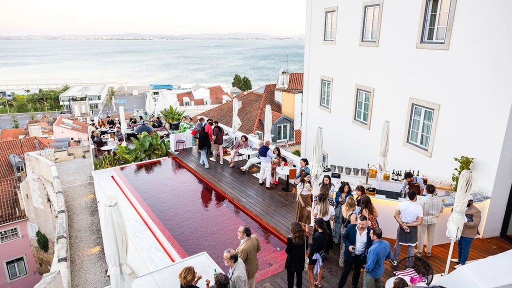 Luxury boutique hotel overlooking Lisbon's historic Alfama district, featuring traditional Portuguese tiles, warm terracotta rooftops, and sunset-lit cobblestone streets