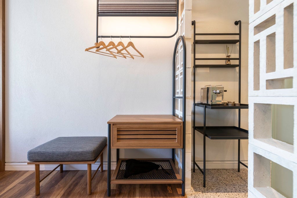 Modern, minimalist hotel room with warm wooden furnishings, crisp white linens, and soft ambient lighting, showcasing elegant Greek design in Athens.