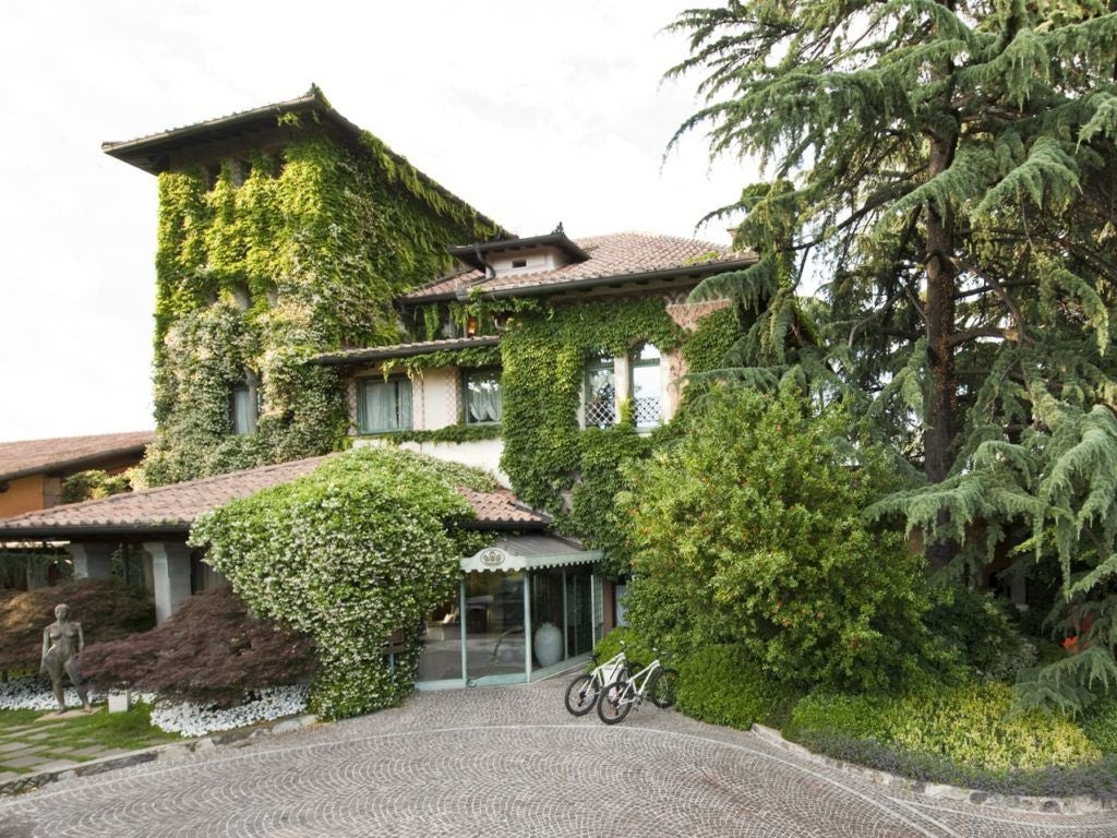 Luxurious Italian countryside resort with elegant stone villa, surrounded by verdant vineyards and rolling hills near Lake Scenset