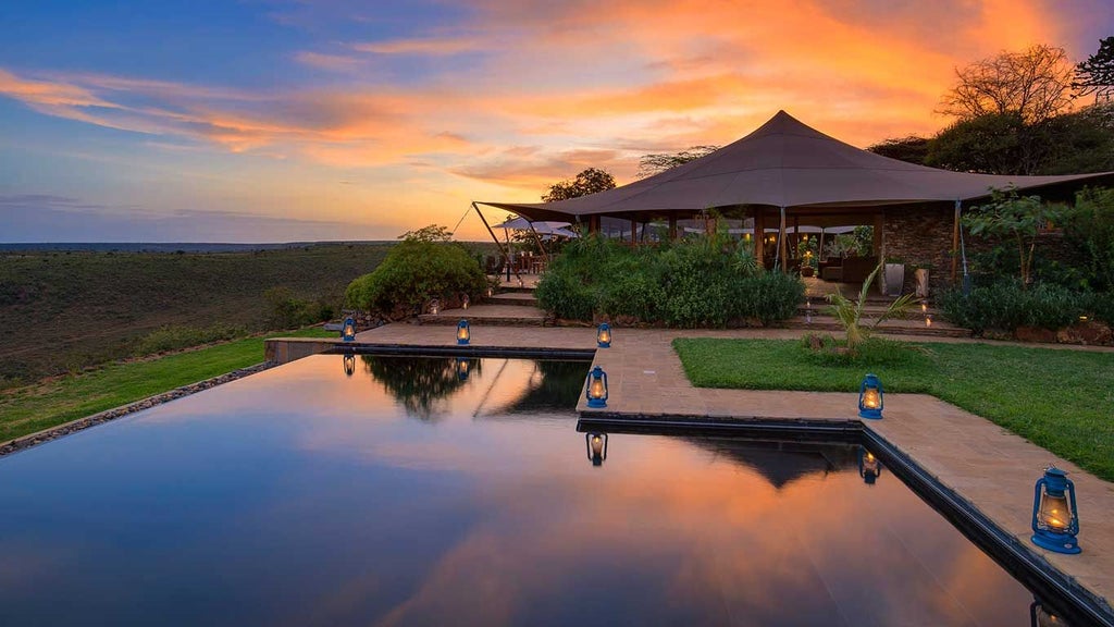 Luxurious safari tents overlooking dramatic Laikipia wilderness, with elegant canvas structures nestled against rugged African landscape and distant mountains.