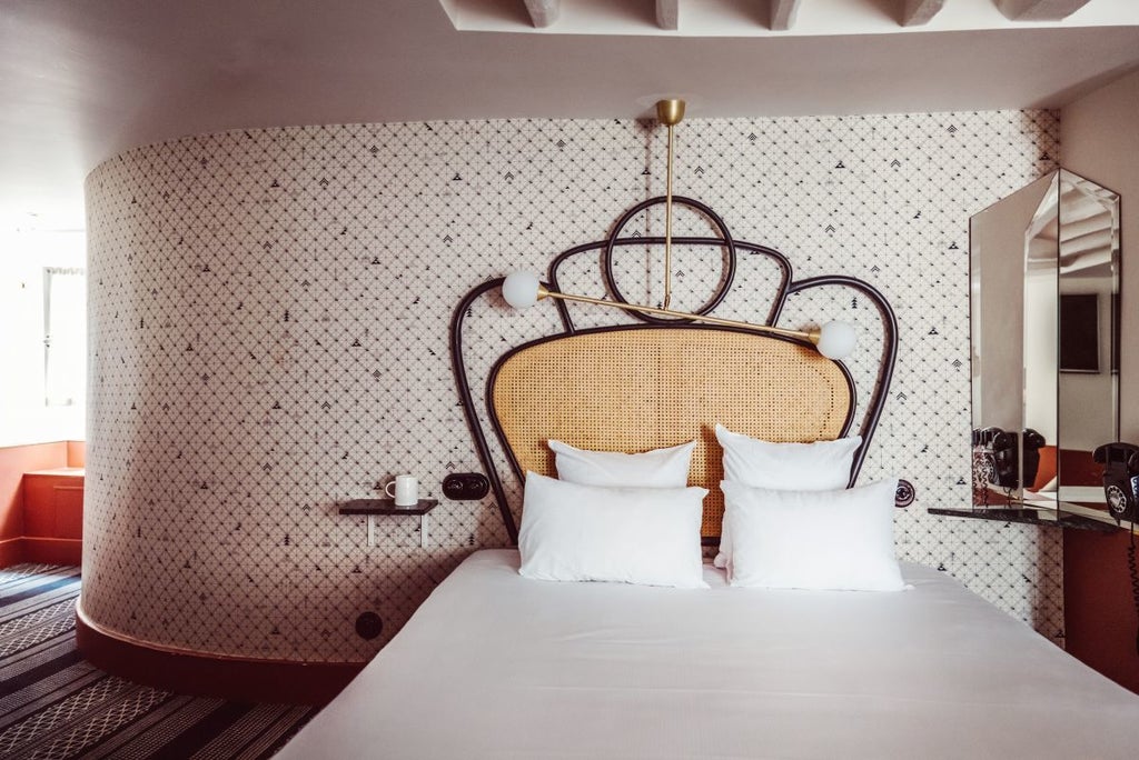 Elegant junior suite at Hotel Panache in Paris, featuring plush white bedding, modern design, and soft neutral tones with chic Parisian architectural details