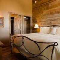 Rustic wooden cabin interior with panoramic windows overlooking scenic mountain landscape, featuring elegant western-style furnishings and warm, inviting decor