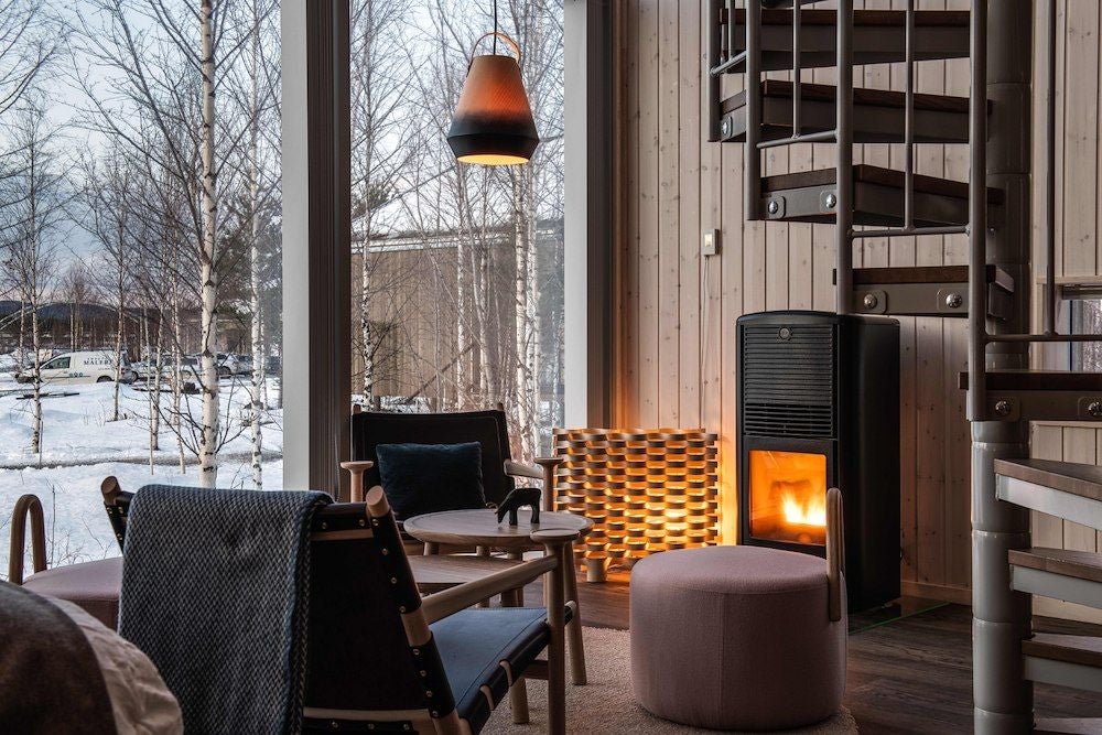 Minimalist Scandinavian suite with wooden interior, floating cabin design, large windows overlooking snowy Nordic landscape at Arctic Bath hotel in Sweden