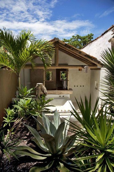 Rustic luxe wooden bedroom with traditional Brazilian design, warm earth tones, and handcrafted details at UXUA Casa Hotel's serene accommodation in Trancoso